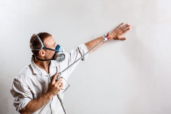 Маляр грунтует стены перед покраской