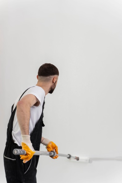 Маляр наносит грунтовку на стену